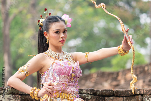 Young woman dressed as goddesses with golden bow and traditional costume celebrates songkran queens festival with grace and beauty outdoor setting