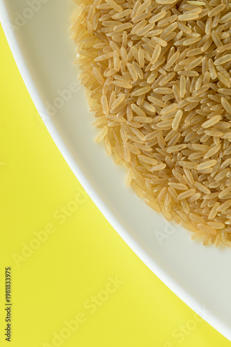 VISTA PARCIAL DE UN PLATO CON ARROZ (Oryza Sativa) SOBRE FONDO AMARILLO