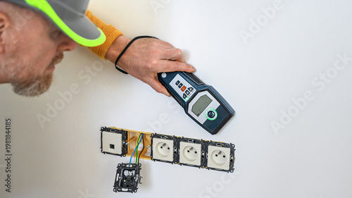 Electrical installation. The electrician's hand using a wall scanner for checking electrical wires in the wall. Metal detector.