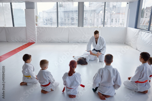 Fotografie Children seated in semicircle focusing on instructor demonstrating techniques