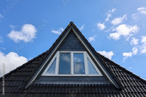 Fotografía Building roof with dormer window against blue sky
