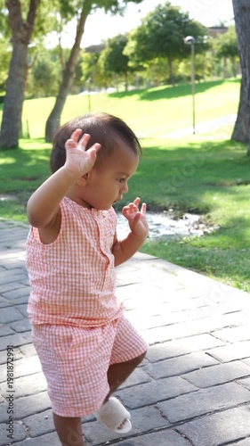 Adorable little baby girl dancing in a sunny public park