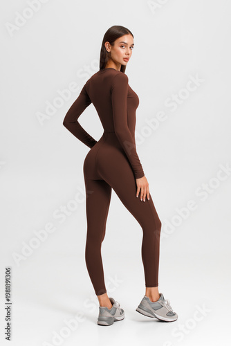 Athletic woman in jumpsuit. Fitness girl on the gray background