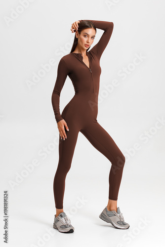 Athletic woman in jumpsuit. Fitness girl on the gray background