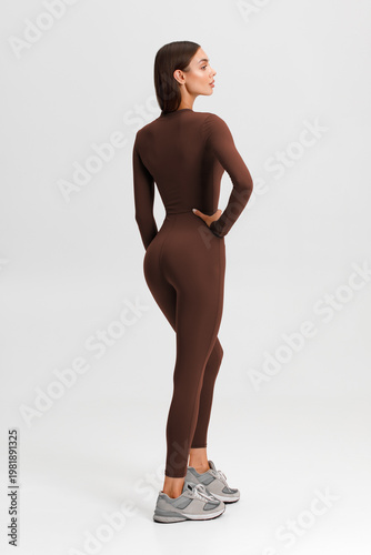 Athletic woman in jumpsuit. Fitness girl on the gray background