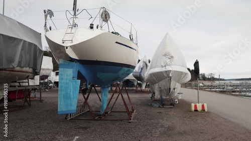 Yachts stored on land under tarps on stands coastal marina off season boat storage maintenance and protection concept maritime industry calm harbor environment