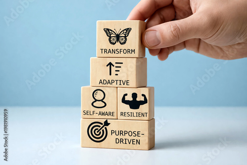 Wooden blocks with transformative icons are stacked by a person to symbolize personal growth and the mental development required for achieving long-term professional success.