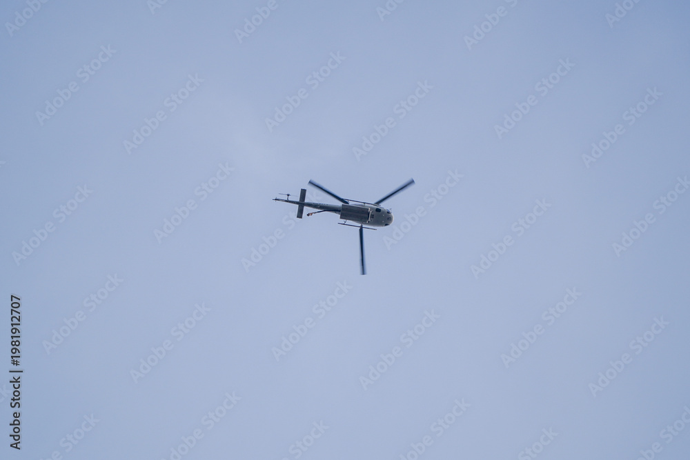 Fototapeta premium Military or Utility Helicopter with Rotor Blur Flying in a Clear Blue Sky