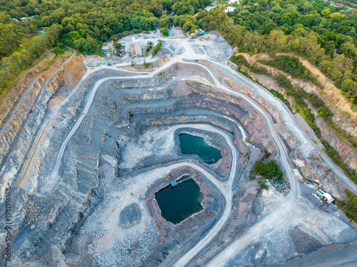 Canvastavla Aerial drone perspective of a vast open-cut quarry with deep blue-green water pits amidst a dense green bushland landscape