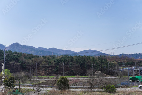 Expansive View of Blue Mountains, Lush Trees, Power Lines, and a Quiet Rural Road