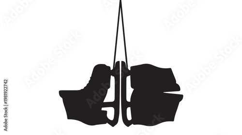 Silhouette of ice skates hanging on wall hook in minimalist black and white composition
