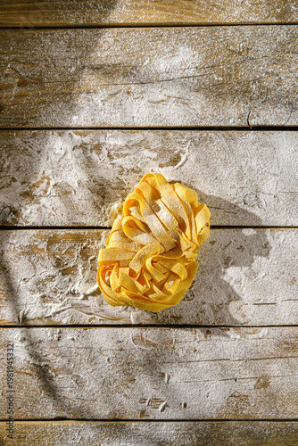 raw fettuccine on a wooden table with flour