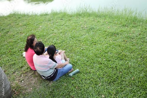 High Angle View of Asian Family Sitting by the Lake in Park