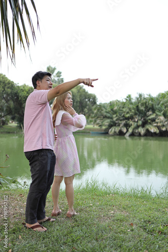 Asian Man Showing Scenic View to Partner by the Water