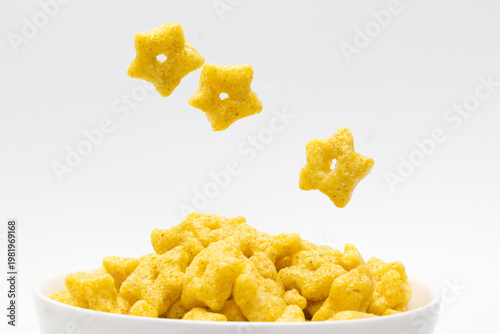 Cereal en forma de estrella cayendo en un bol sobre fondo blanco