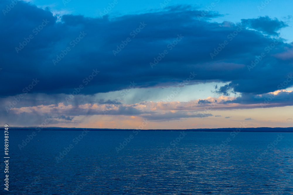 Fototapeta premium Amazing sunset seen over Lake Constance near the city of Rorschach in the Sankt Gallen region in Switzerland with an impressive rolling cloudscape full of unpredictable weather and snow showers in ear