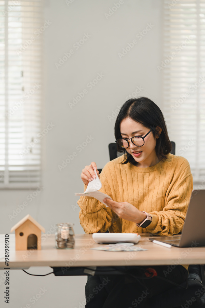 Photography Young Asian woman managing home budget and financial planning with a house model