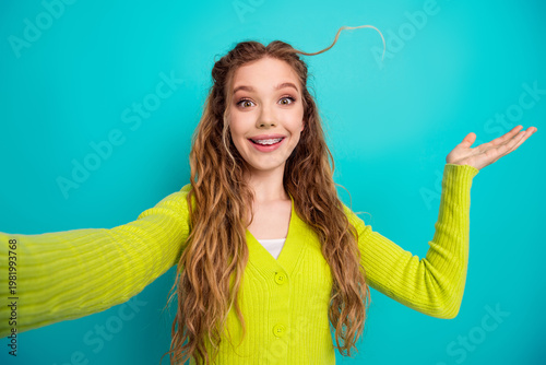 Canvas Print Cheerful young woman with long wavy hair and braces taking a fun selfie in a bri