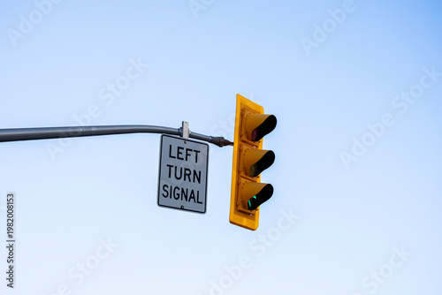 Obraz na płótnie Traffic light with left turn signal sign mounted on a street pole against a clear blue sky