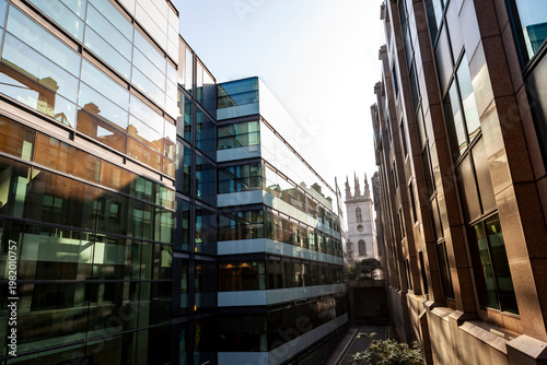 Modern glass buildings contrasting with a traditional church spire in the city of london