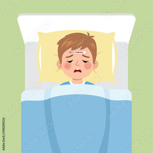 A young boy lying in bed with a thermometer on his forehead, feeling very sick