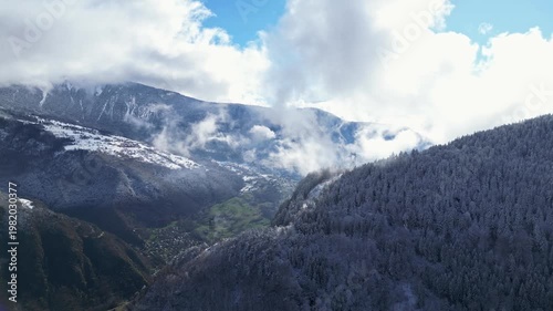 Aerial view of Tarentaise Valley with highway, alpine villages and snowy mountains covered in fog in the French Alps, Savoie, France.