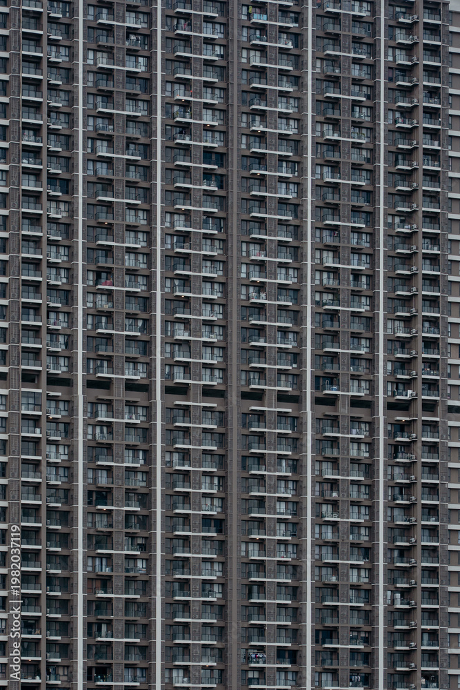 Fototapeta premium Close-up view of a massive modern residential apartment facade showcasing dense balconies, windows, and repetitive architectural patterns.