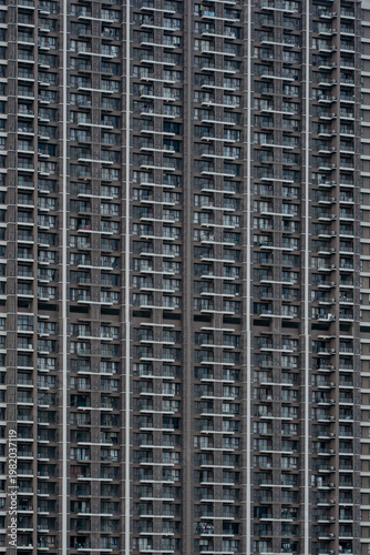 Close-up view of a massive modern residential apartment facade showcasing dense balconies, windows, and repetitive architectural patterns.