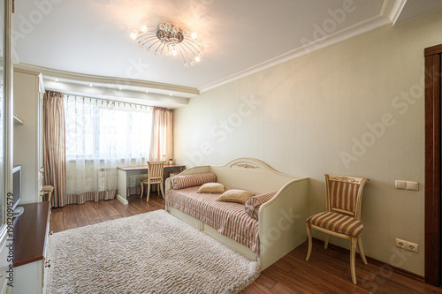 ozy bedroom with a cream daybed, striped cushions, plush beige carpet, wooden desk, striped chair, sheer curtains, and a crystal chandelier