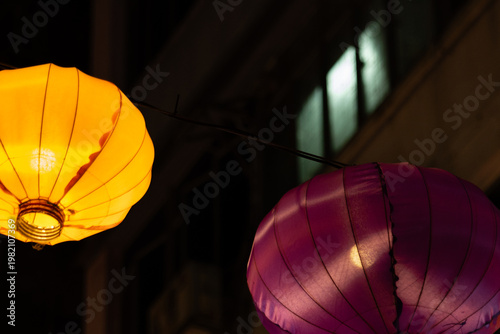 Two glowing Chinese lanterns — one yellow, one pink — hanging at night at Temple Street Night Market, Kowloon, Hong Kong