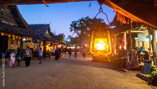 Village street lit by lantern at dusk; people walking and buildings nearby