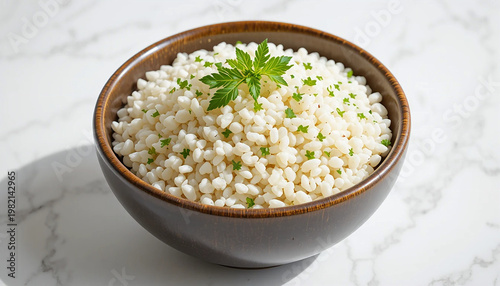 bowl of white rice garnished with fresh green herb on marble surface