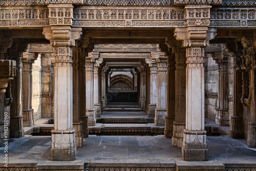 Repeating stone pillars and horizontal beams creating a corridor of symmetry at Adalaj Stepwell, Adalaj ni Vav, Ahmedabad, Gujarat, India, Asia.
