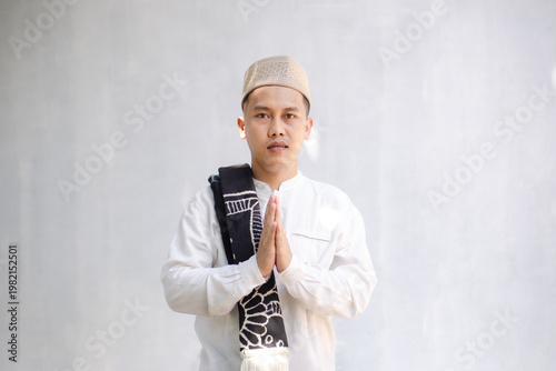 Фотография Portrait of a devout Muslim man in white koko shirt and peci, making a greeting