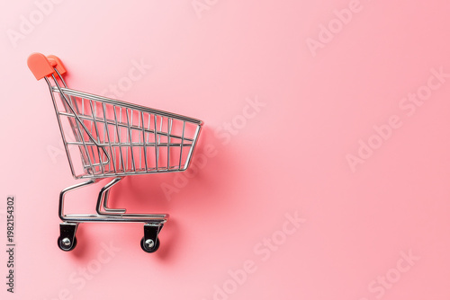 Empty shopping cart placed on pink background, creating playful and vibrant shopping theme