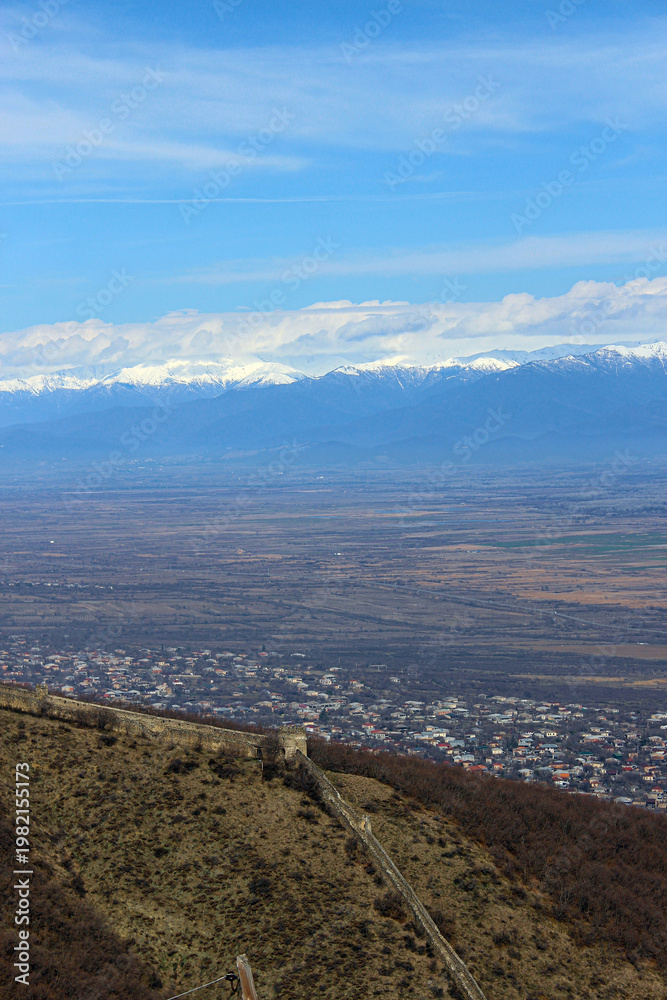 Obraz premium Aerial view of the old city's fortress wall. The village, the Alazani Valley, the Caucasus Range, and snow-capped mountains in the background. Sighnaghi, Kakheti, Georgia