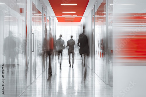 A blurred motion shot captures several figures walking down a modern, brightly lit hallway with a striking red ceiling and glass walls, conveying a sense of business and activity.