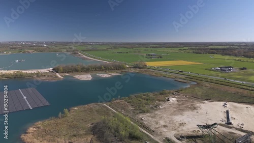 Wide aerial reverse reveal of floating solar farm on a lake