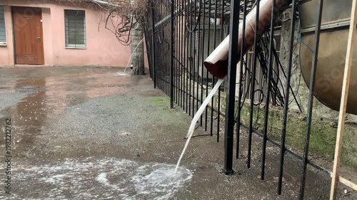 Rainwater flows down drainpipes during a downpour in the old town.