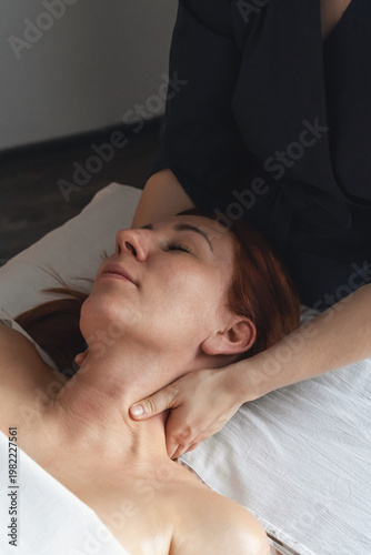 Woman receiving relaxing professional neck and shoulder massage therapy. Client enjoying rejuvenating massage treatment in tranquil spa environment