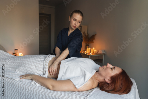 Woman receiving relaxing stomach massage from a therapist in a tranquil spa room with warm candlelight. Promoting wellness and health