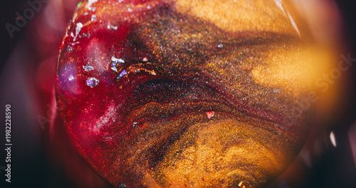 Sphere flowing paint. Golden round texture. Defocused yellow red purple color spatter glitter liquid crystal floating on abstract light background.