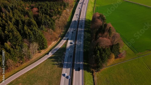 Drone shot of the Bundesautobahn 95 in Southern Germany. Modern road infrastructure and traffic flowing through the scenic Bavarian landscape towards the Alps on a sunny summer day.