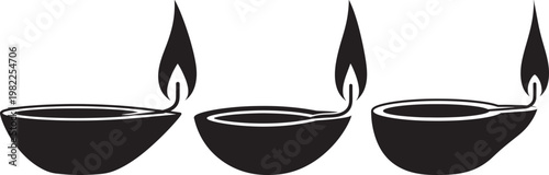 Three black diya lamps with flames burning for Diwali festival celebration