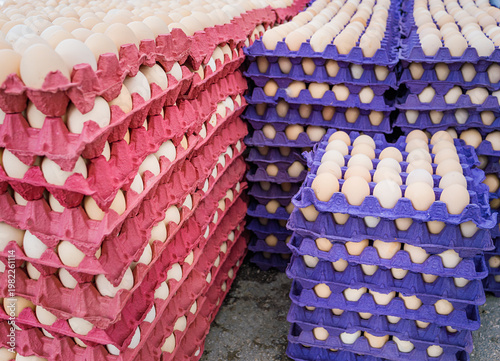Bild auf Leinwand Large stack of fresh organic chicken eggs in colorful red and purple cardboard trays at local farmers market, wholesale poultry production, agricultural food supply background for retail and cooking