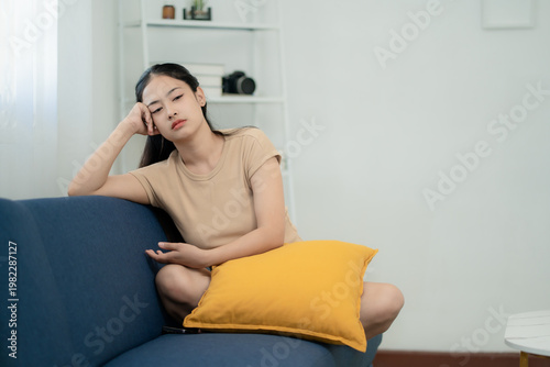 Billede på lærred Asian woman feeling bored and stressed sitting on sofa at home, mental health, l