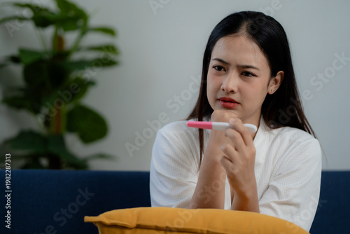 Cuadro en lienzo Asian woman looking at pregnancy test with surprised expression at home, discove