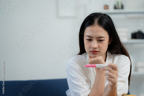 Obraz na plátne Asian woman looking at pregnancy test with surprised expression at home, discove