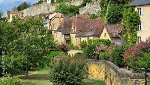 View to the village of Beynac-et-Cazenac, Dordogne, France with flowering shrubs from the river side walkway during summer