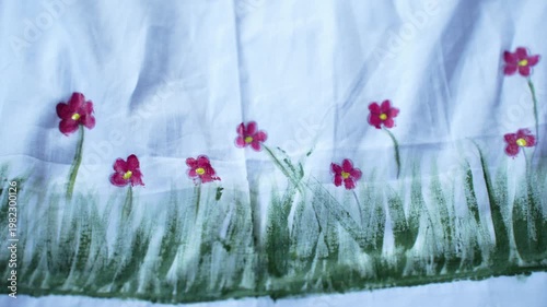 Traditional Bangladeshi hand-painted fabric on a child girl’s white gown with colorful folk art patterns, vibrant textile details, cultural fashion design, and artistic dress decoration.